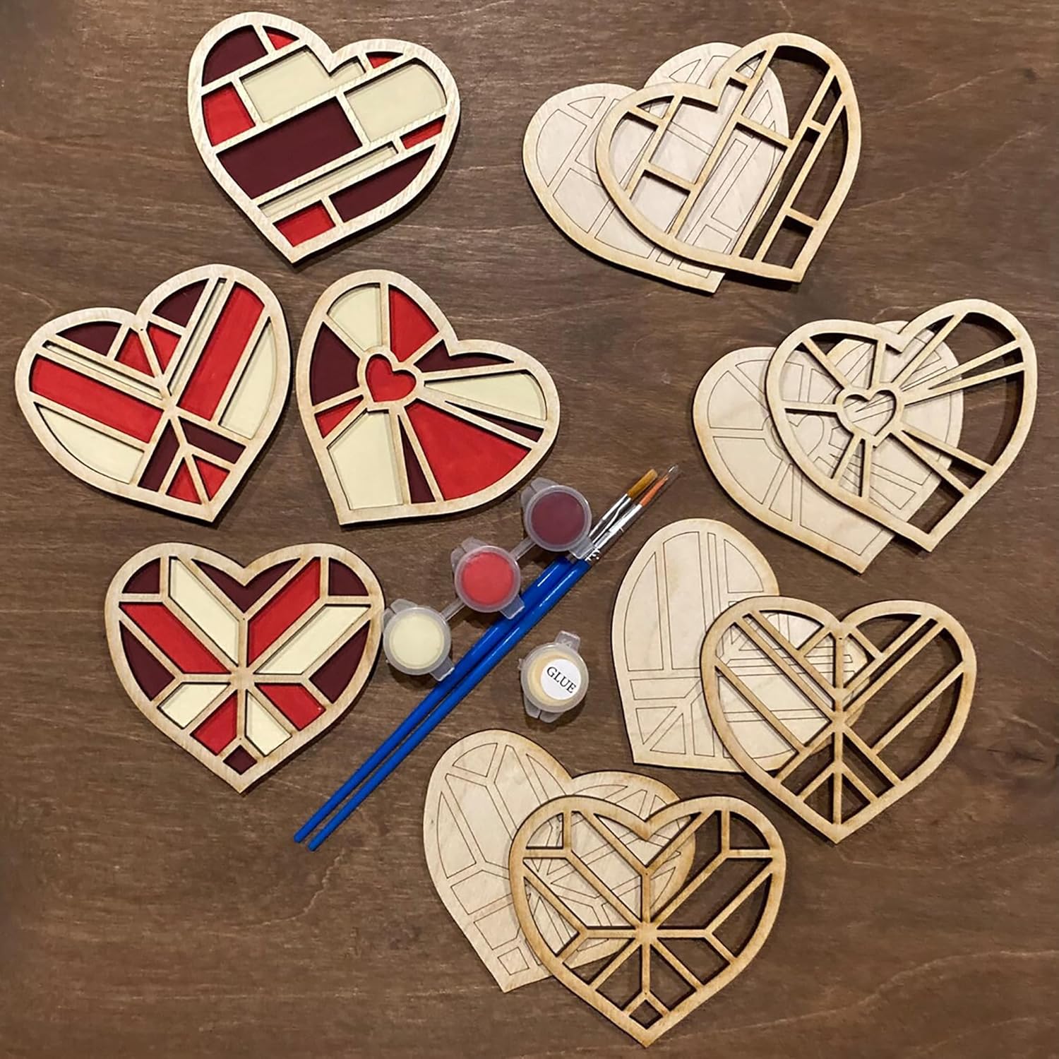 Set of wooden heart-shaped templates with paint supplies on a wooden surface