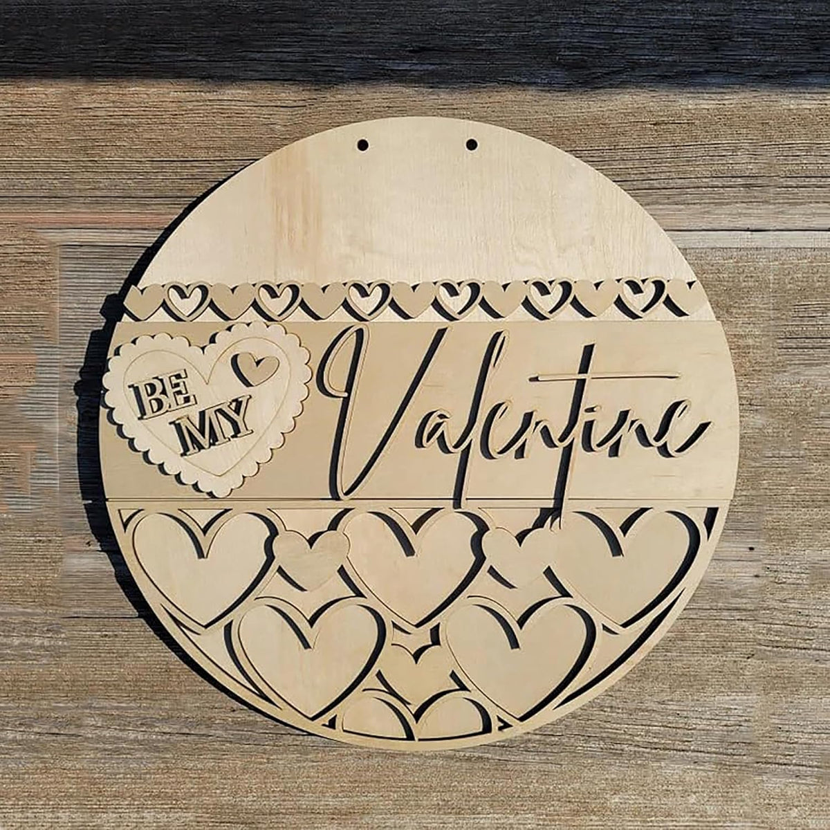 Wooden round decorative item with 'Be My Valentine' text and heart designs on a wooden surface.