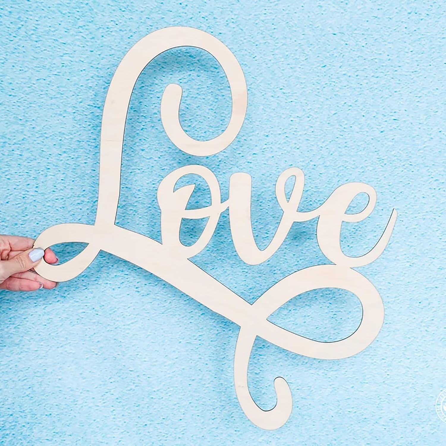 Wooden 'love' sign held against a light blue background