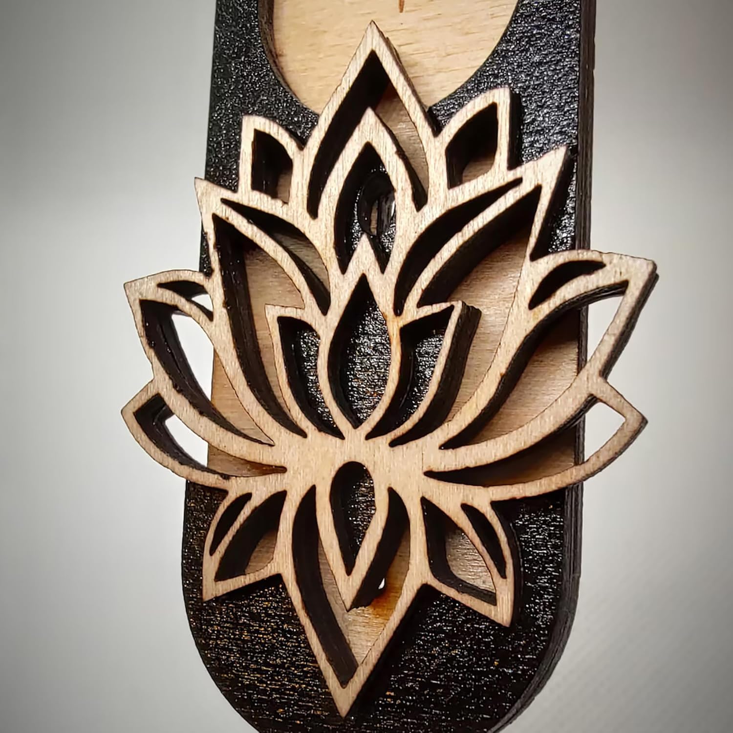 Wooden sandal with a detailed lotus flower design on a gray background