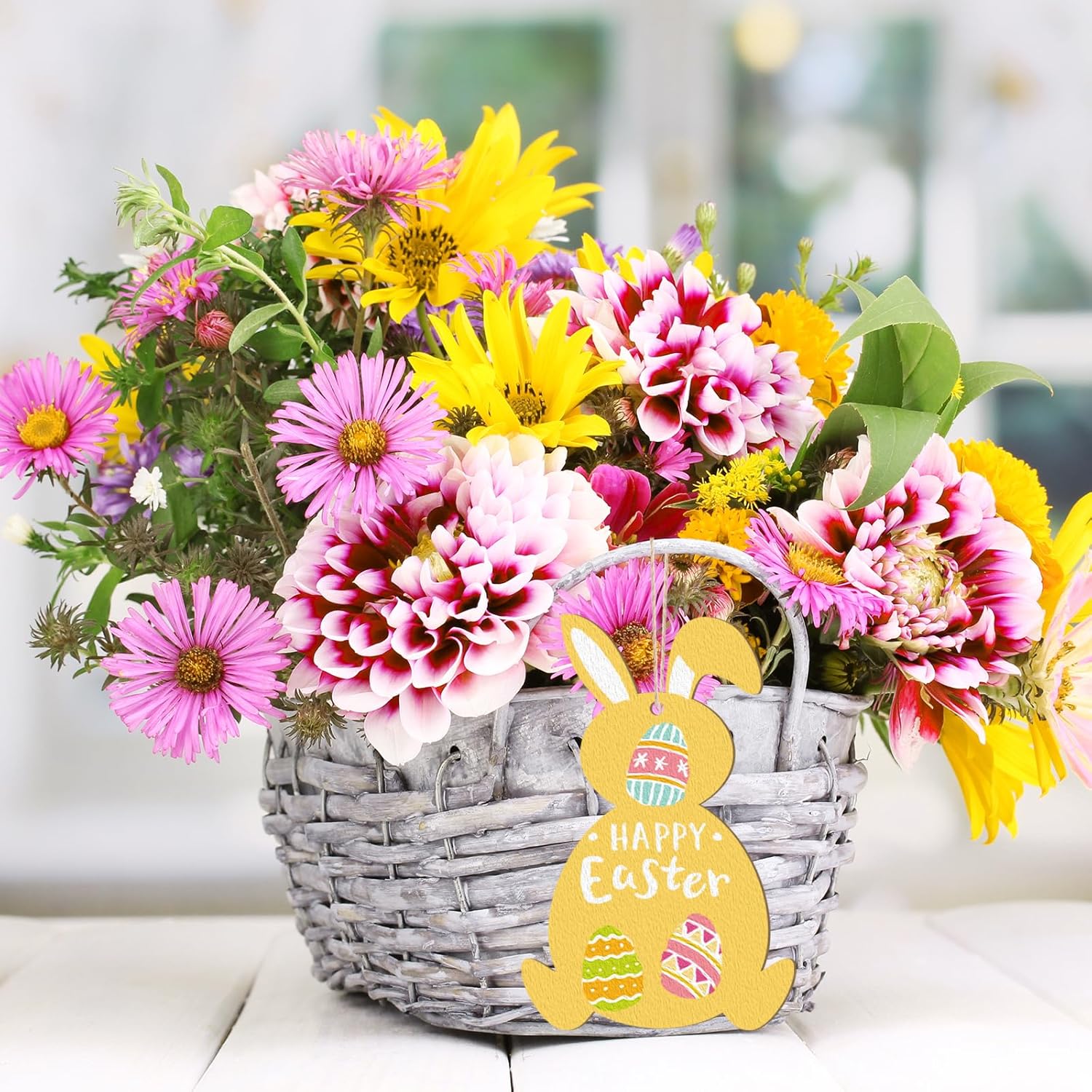 Basket of flowers with a 'Happy Easter' bunny tag on a blurred background