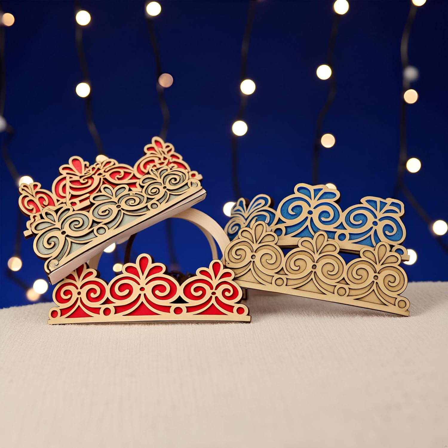 Decorative wooden tiaras with intricate designs on a blue background with string lights.