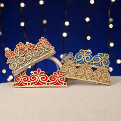 Decorative wooden tiaras with intricate designs on a blue background with string lights.