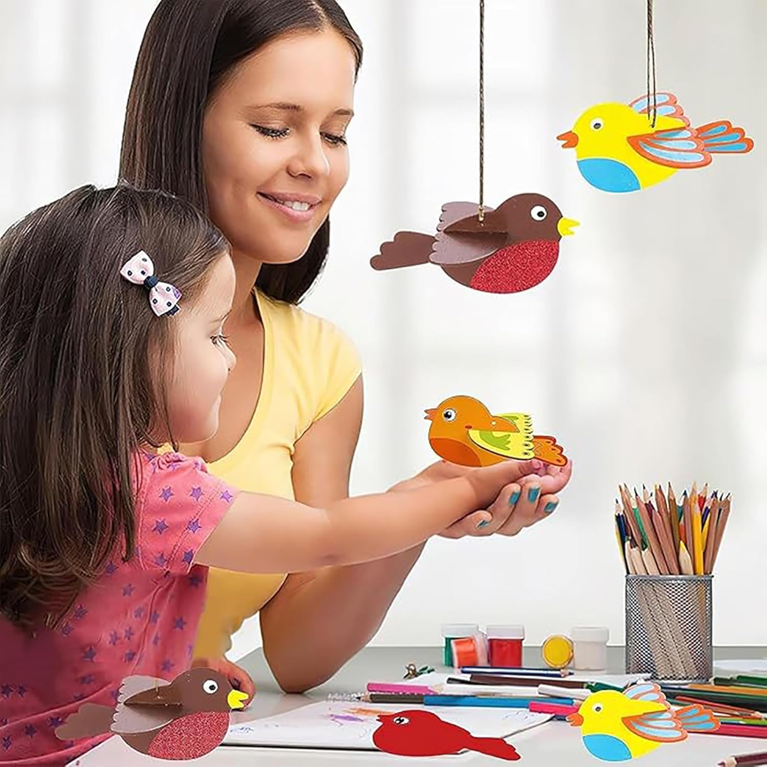 Woman and child playing with colorful bird toys on a table.