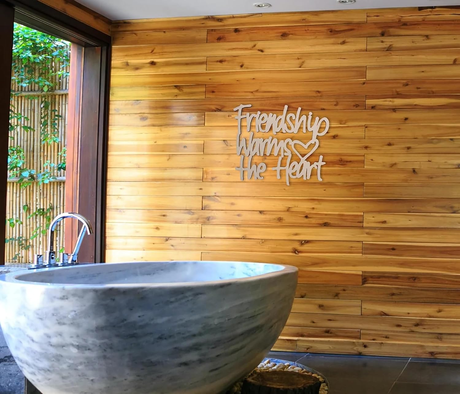 Marble bathtub in a bathroom with wooden wall and 'Friendship Warms the Heart' sign.