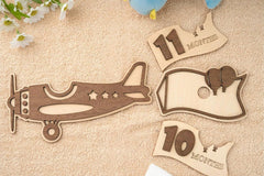 Wooden airplane and milestone cards on a textured surface with flowers.