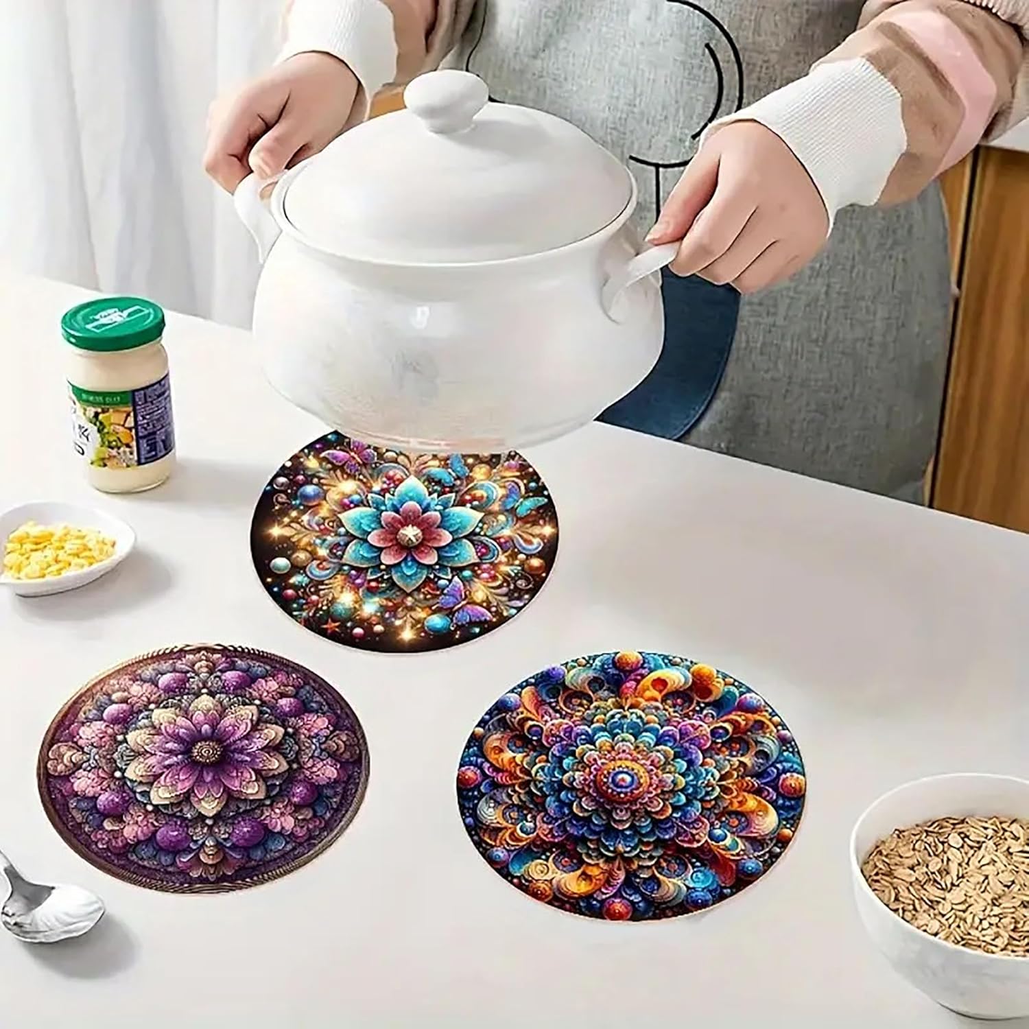Colorful mandala coasters on a table with a person holding a teapot.