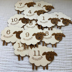Sheep-shaped milestone markers with month labels on a textured surface
