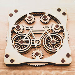 Wooden laser-cut design of a bicycle with gears on a wooden surface