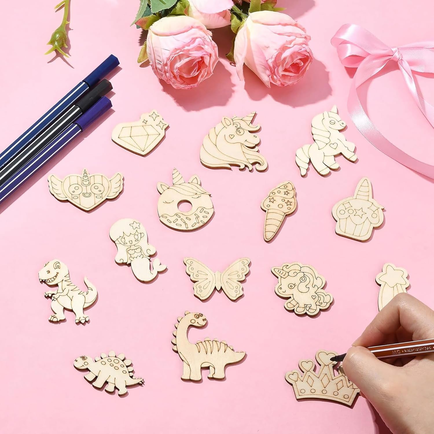 Decorative pins with unicorn, dinosaur, and butterfly designs on a pink surface.