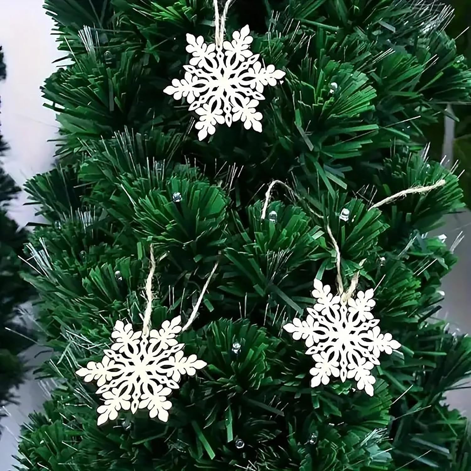 Green artificial Christmas tree with white snowflake ornaments.