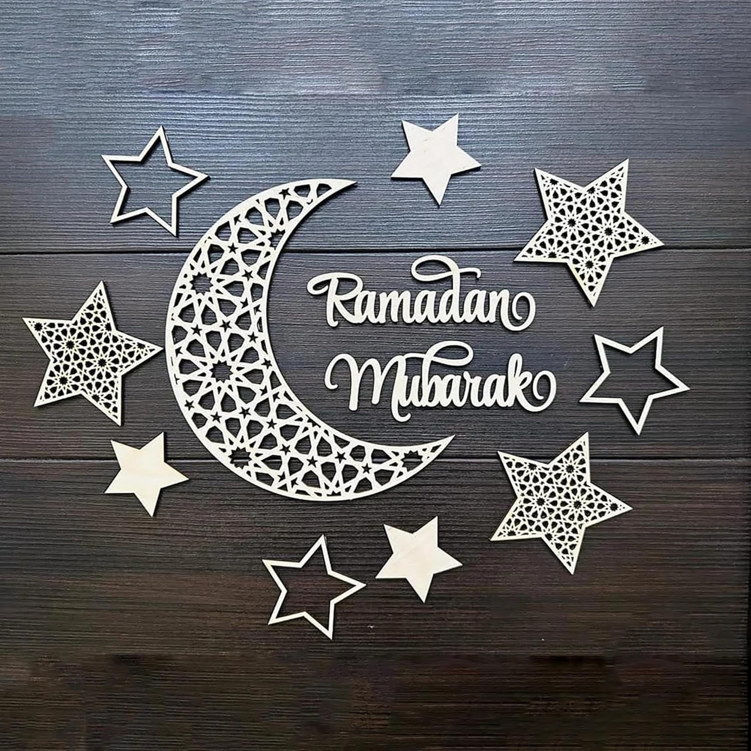 Decorative cutout of a crescent moon and stars with 'Ramadan Mubarak' text on a wooden background.