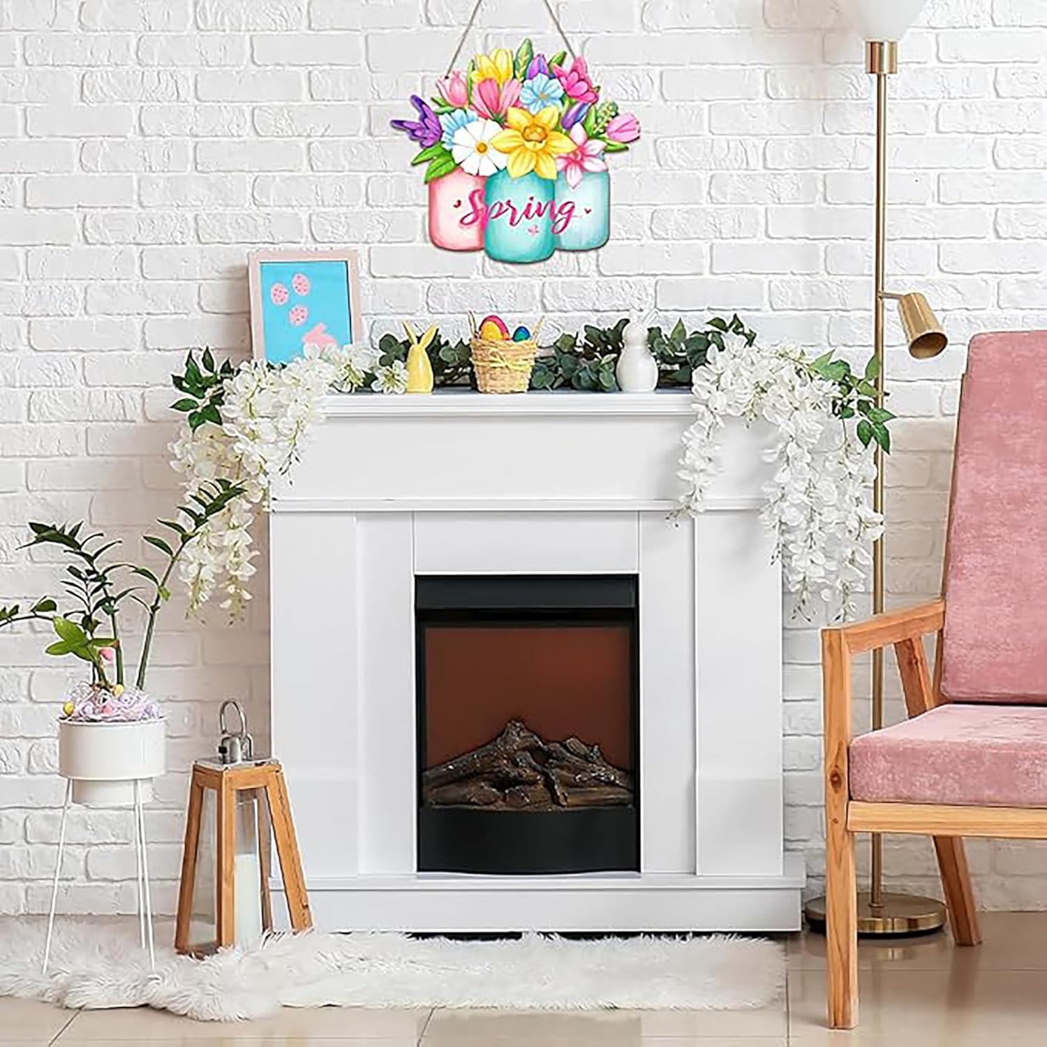 Decorative spring sign above a fireplace with floral arrangements and a pink chair.