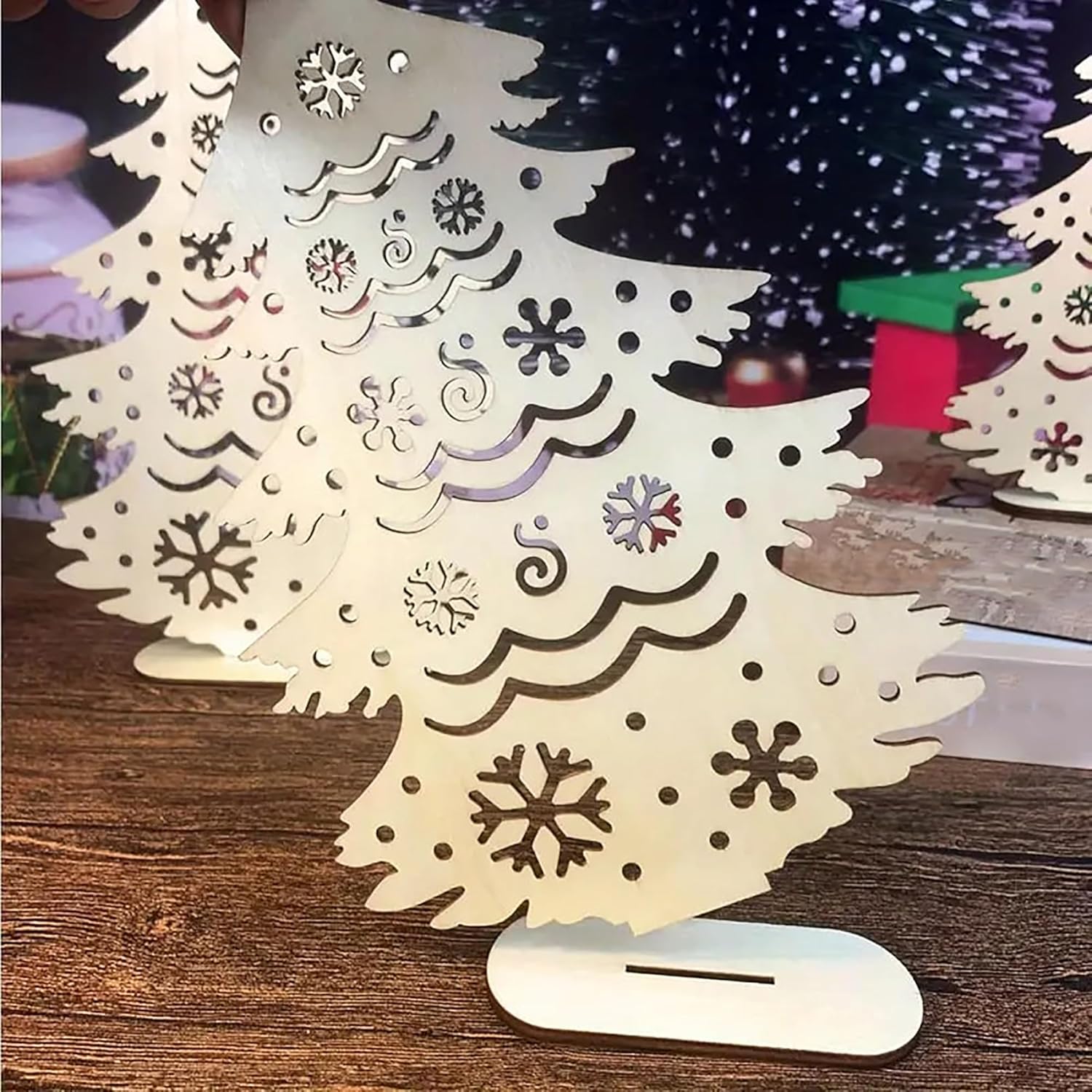 Decorative Christmas tree made of paper with cut-out snowflakes on a wooden surface.