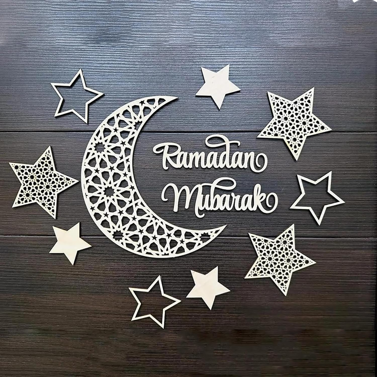 Decorative cutout of a crescent moon and stars with 'Ramadan Mubarak' text on a wooden background.