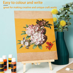 Floral painting on a cardboard board with a vase of flowers and paint bottles in the background.