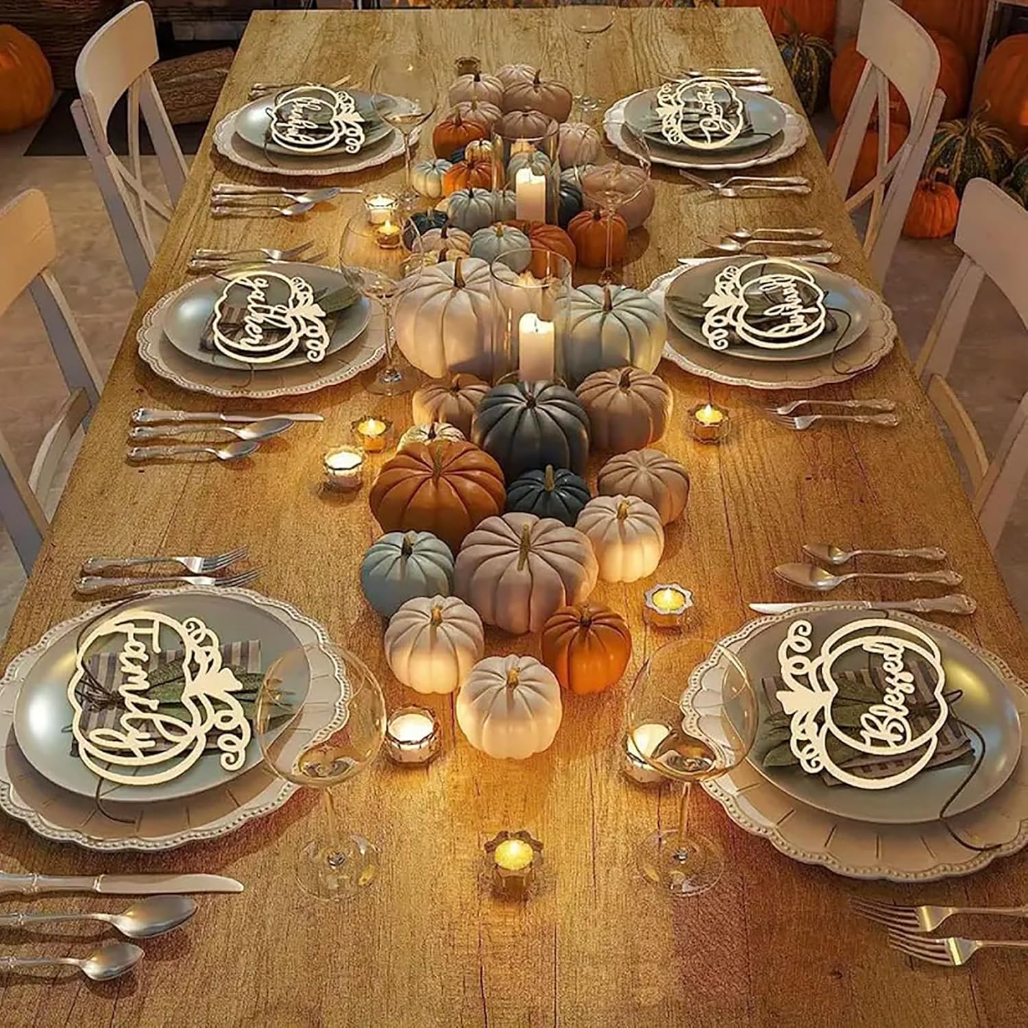 Thanksgiving table setting with pumpkins and candles on a wooden table.
