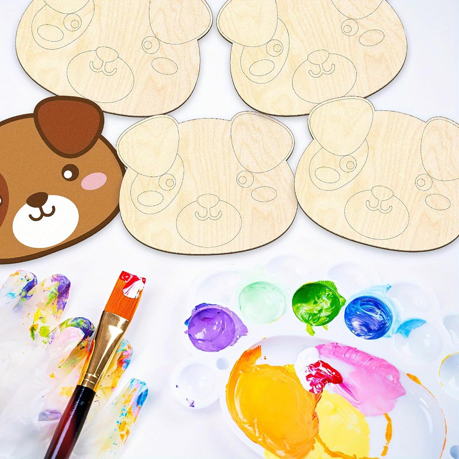 Wooden cutouts of dog faces with paint samples and a brush on a white background