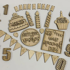 Collection of wooden birthday-themed decorations on a white background