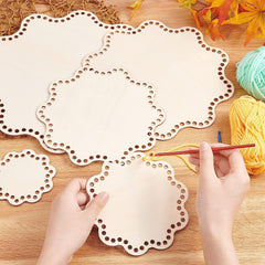 Hands working with crochet hooks and yarn on a wooden surface with decorative cut-out paper.