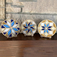 Three decorative coasters with geometric patterns on a wooden surface.