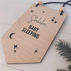 Wooden sign with 'Shhh.. Baby Sleeping' text on a light wooden surface.
