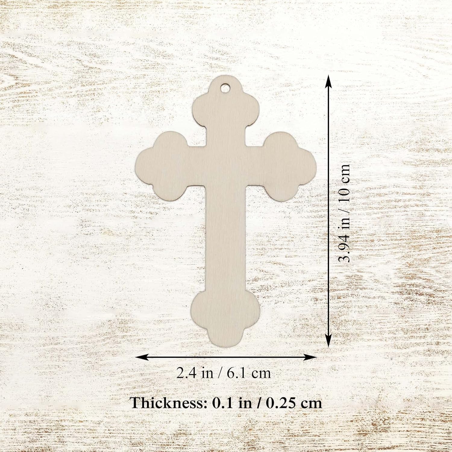 Beige cross-shaped pendant with measurements on a light wood background