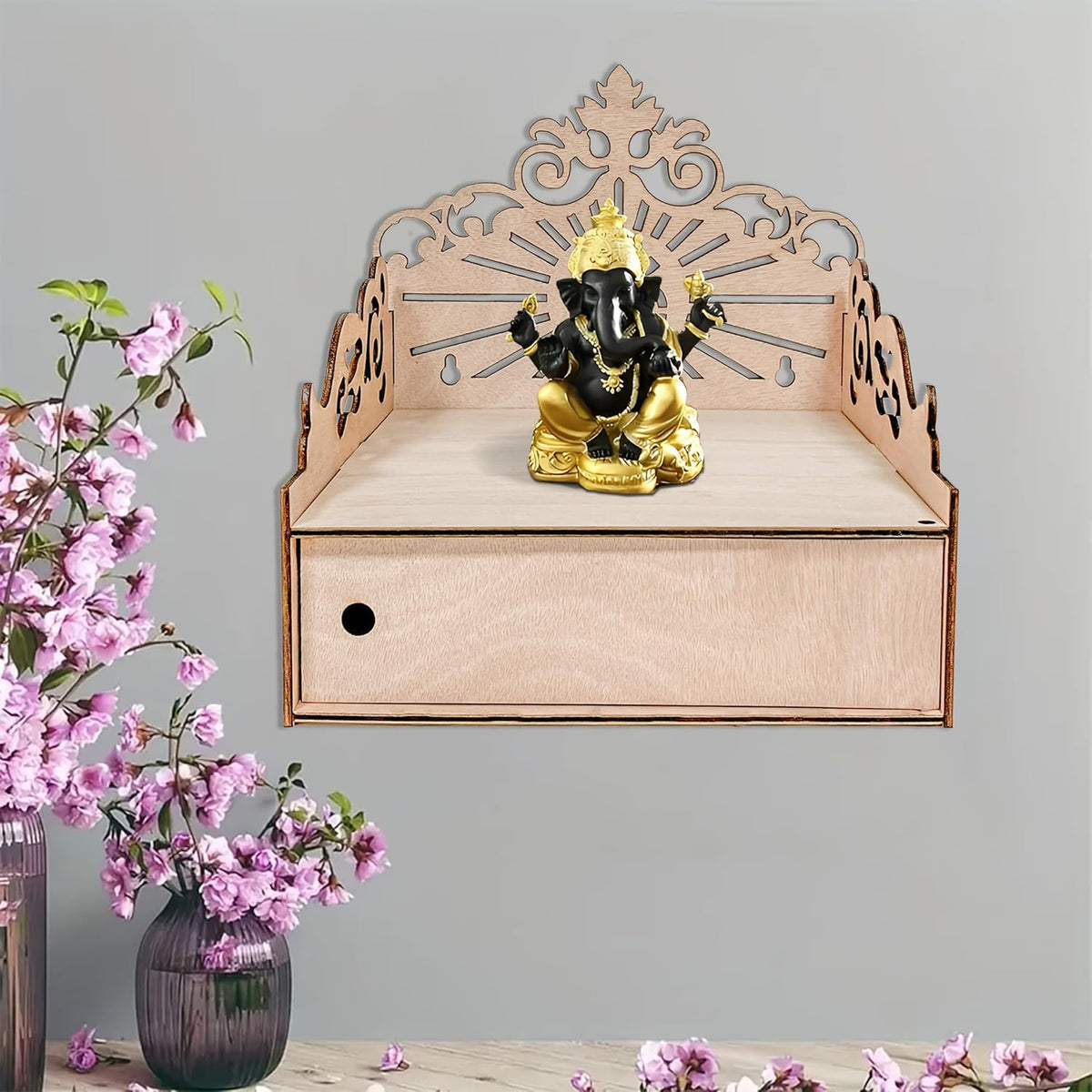 Decorative shelf with a statue of Ganesha and pink flowers on a gray background