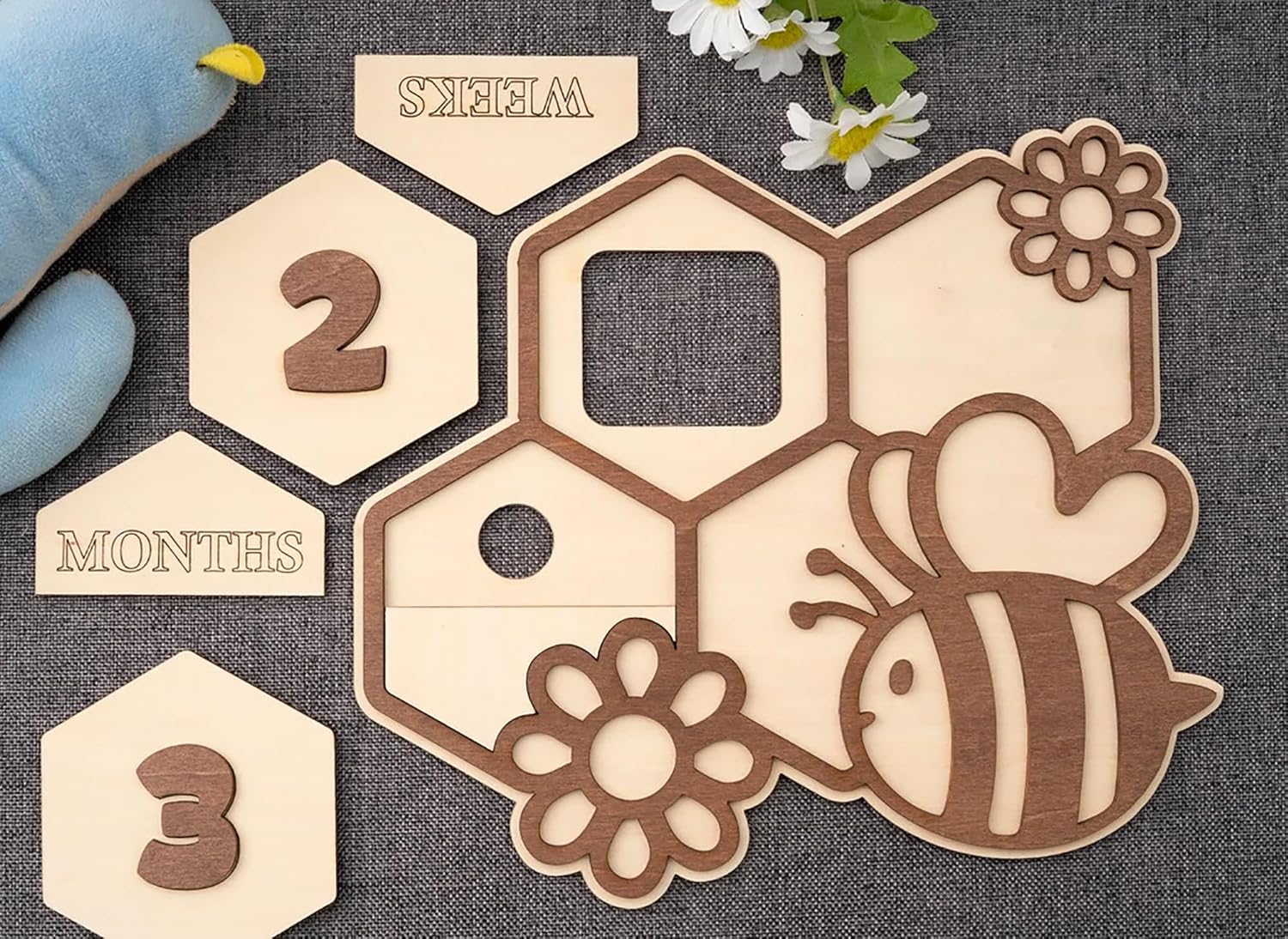 Wooden baby milestone cards with bee and flower designs on a textured surface.