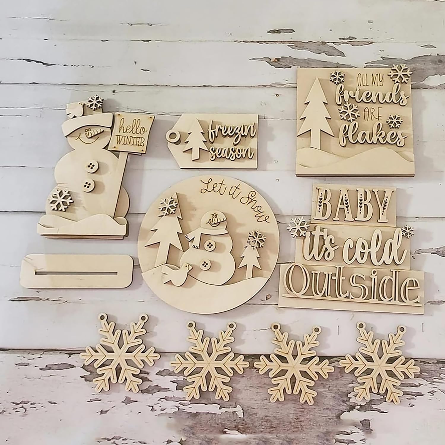Collection of wooden Christmas decorations with text and snowflake designs on a rustic wooden background.