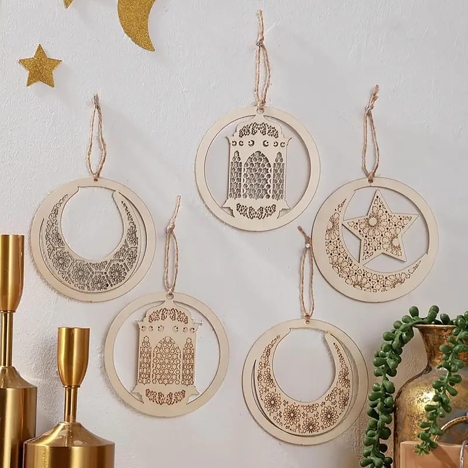 Decorative hanging ornaments with moon, star, and arch designs on a white wall.