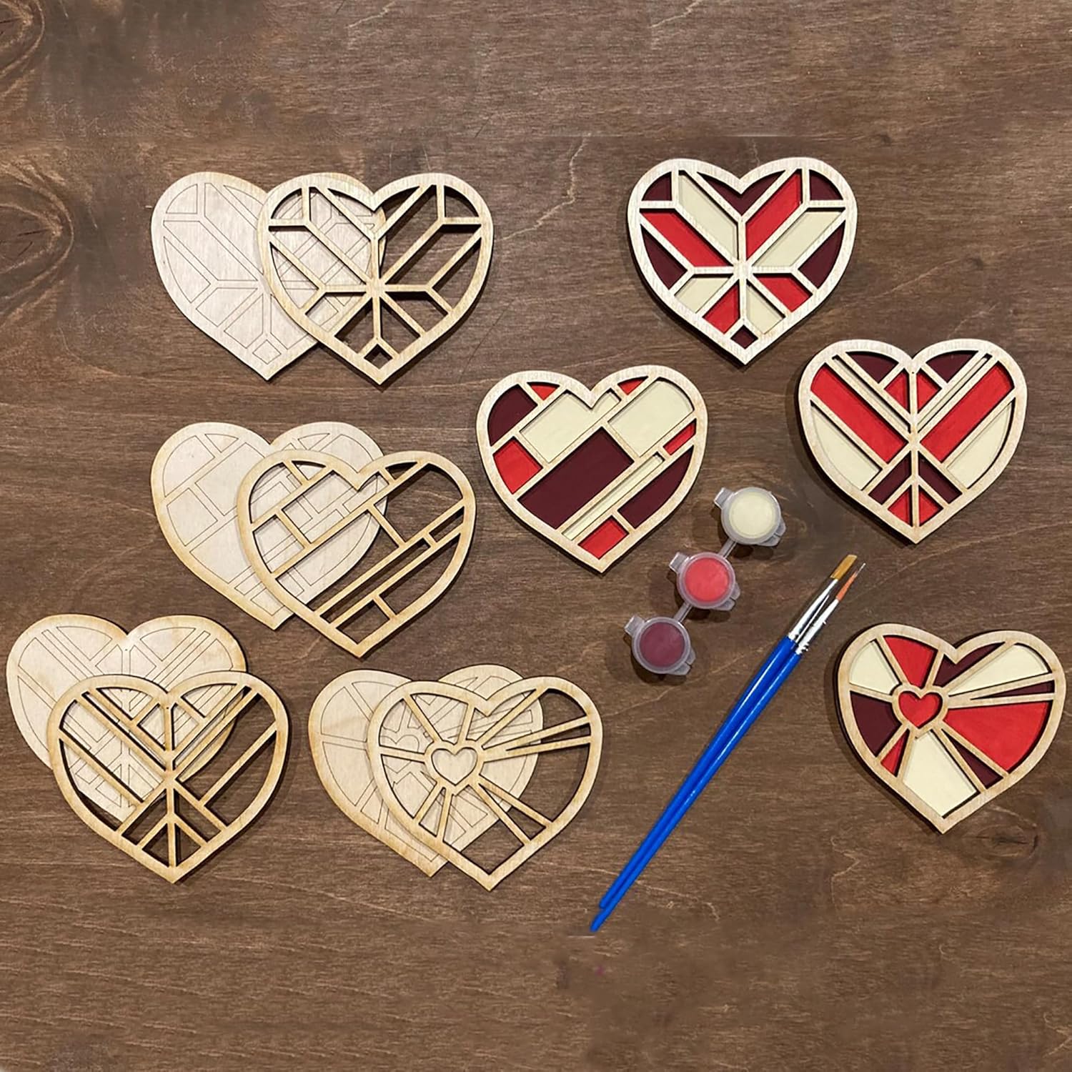 Wooden heart-shaped cutouts with paint and a brush on a wooden surface