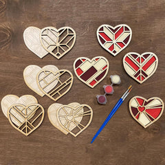 Wooden heart-shaped cutouts with paint and a brush on a wooden surface