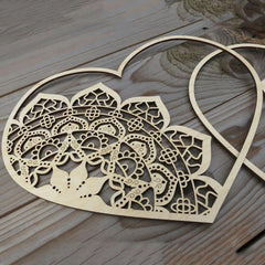Decorative wooden heart with intricate cut-out patterns on a wooden surface