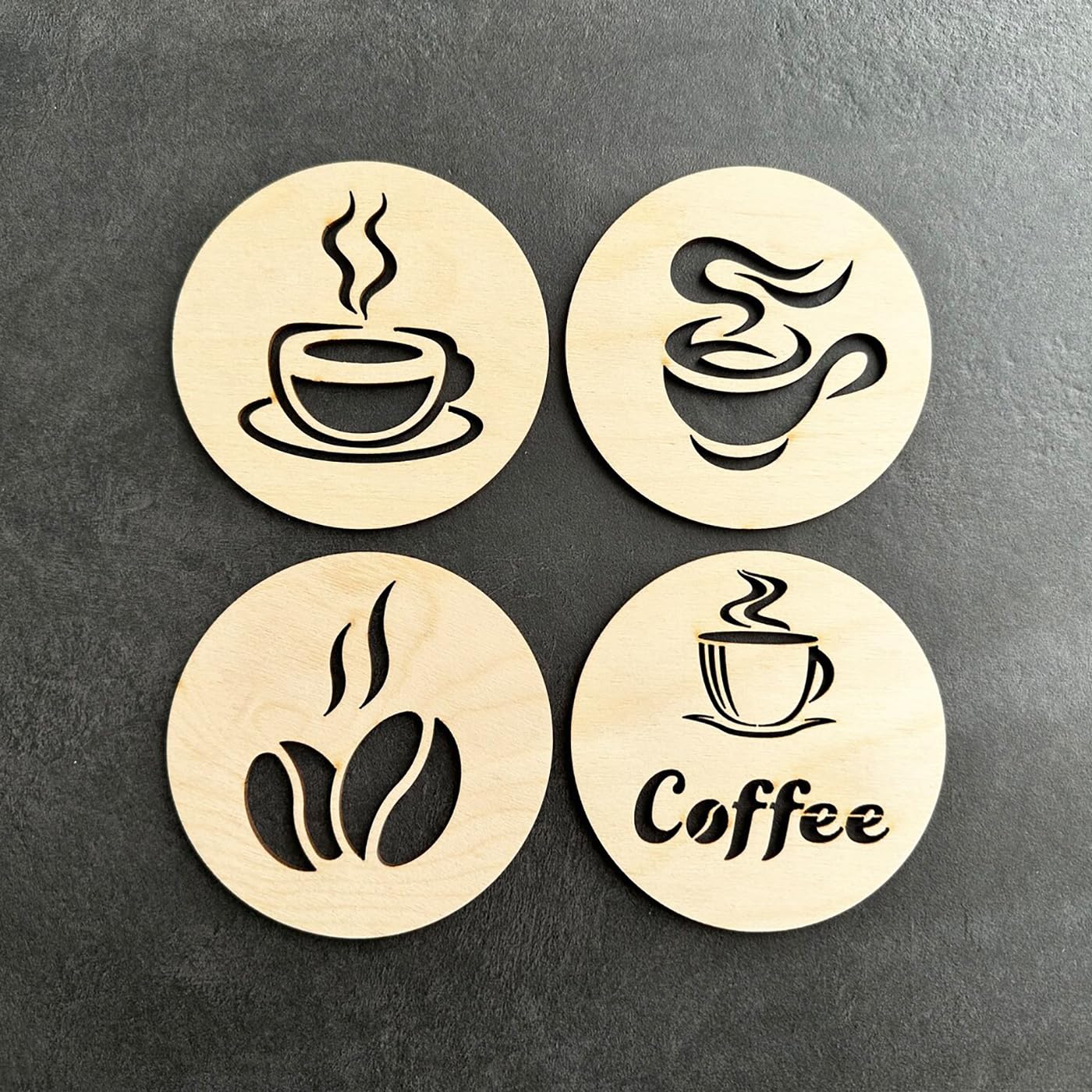 Four wooden coasters with coffee-themed designs on a dark surface