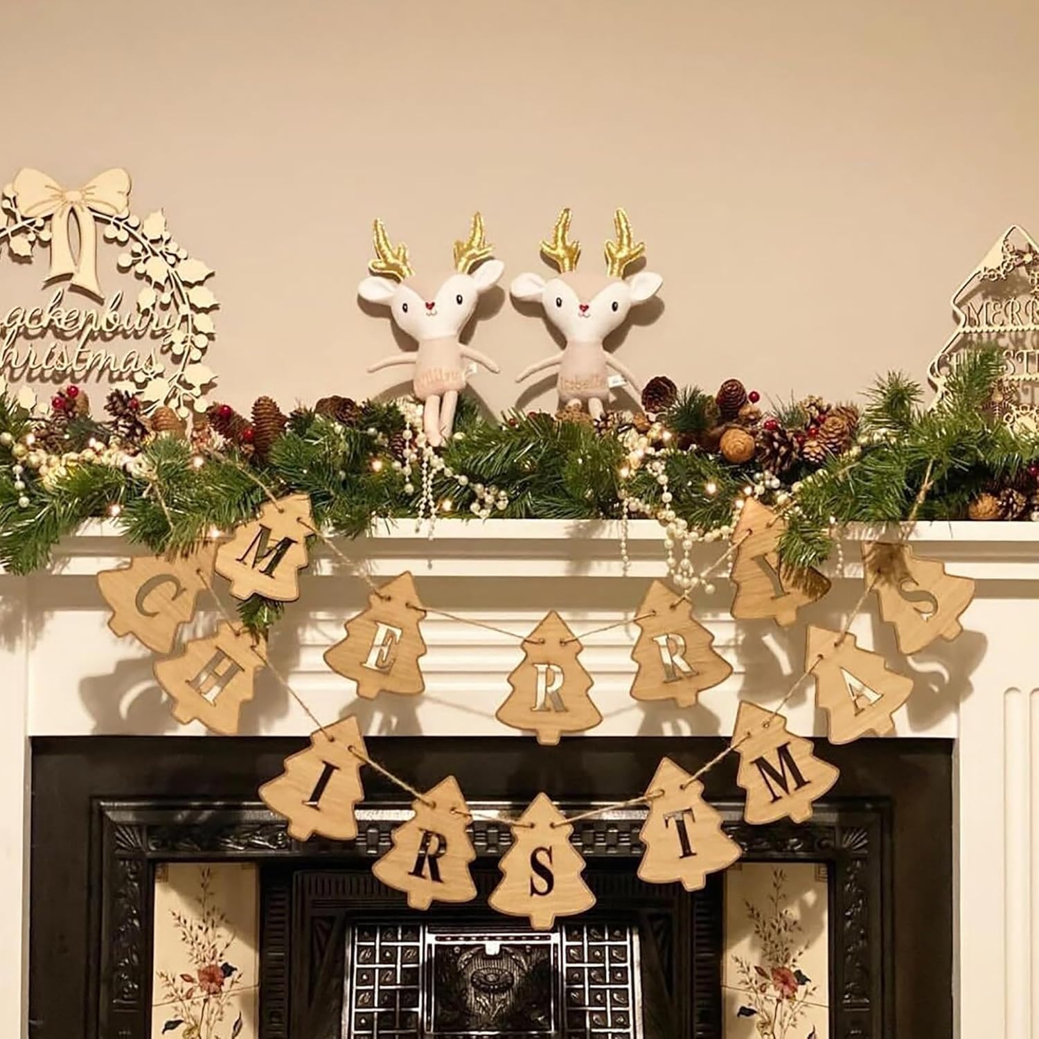 Decorative Christmas mantel with garland, reindeer figurines, and 'Merry Christmas' banner.