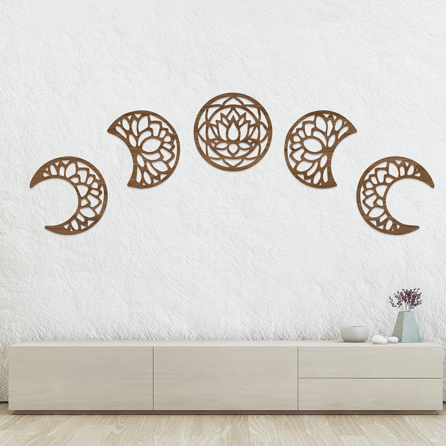 Decorative wall art of moon phases on a white wall above a light-colored cabinet.