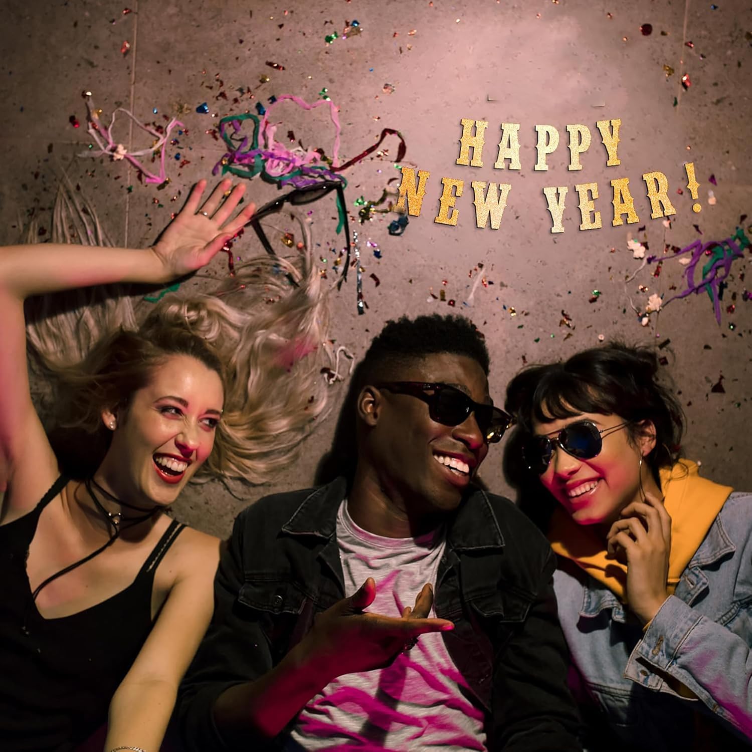Three people celebrating with confetti and 'Happy New Year!' text on a dark background