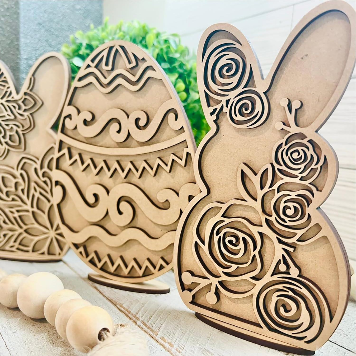 Wooden Easter decorations including a bunny and eggs with floral patterns on a light wooden surface.