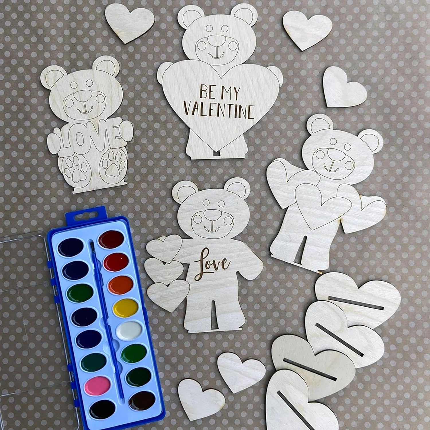 White bear and heart-shaped cutouts with 'Be My Valentine' and 'Love' text, along with a watercolor set on a gray background.