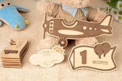 Wooden baby milestone cards with airplane design and teddy bear in the background
