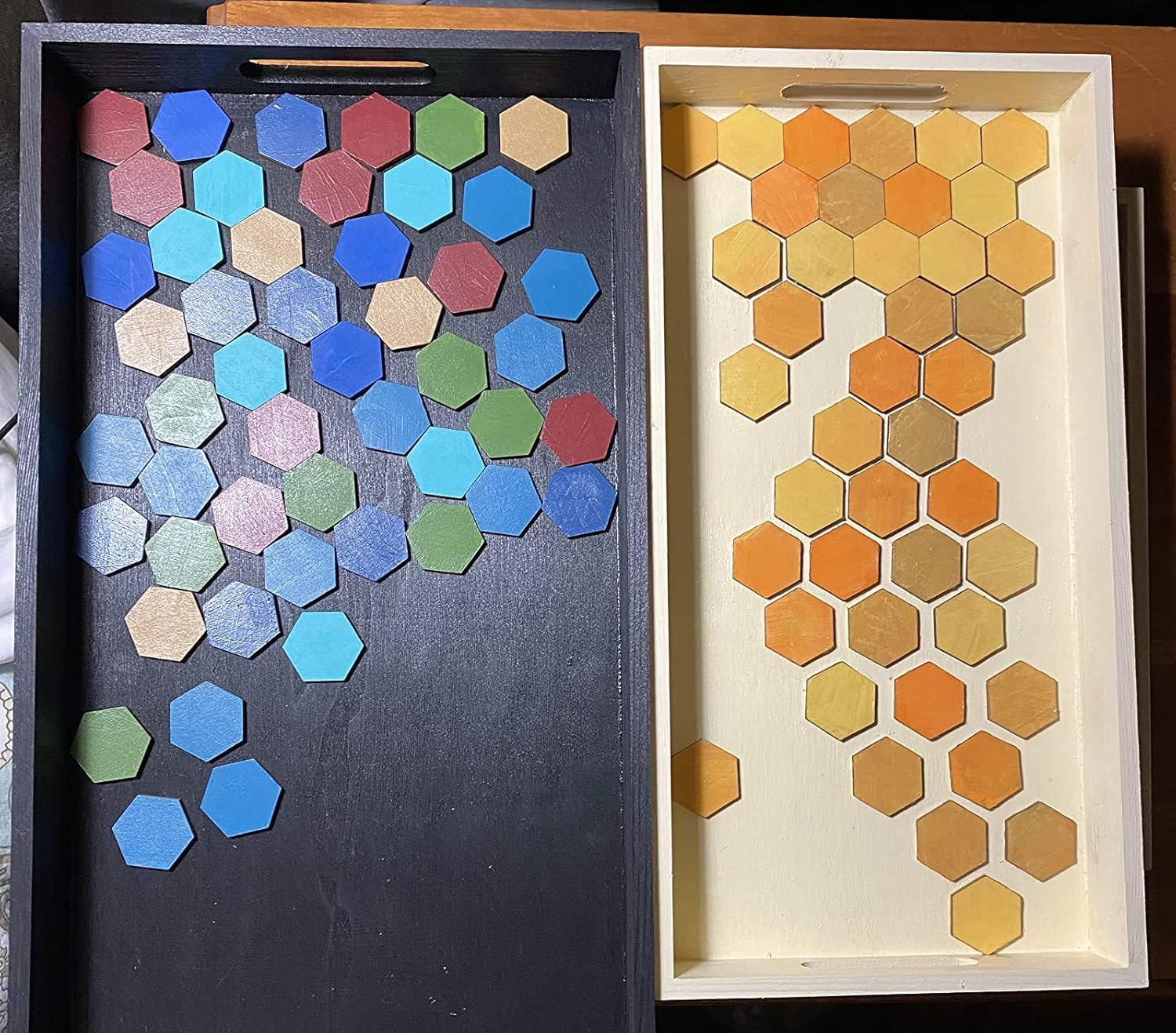 Two trays with hexagonal tile patterns in blue and orange on a wooden surface.