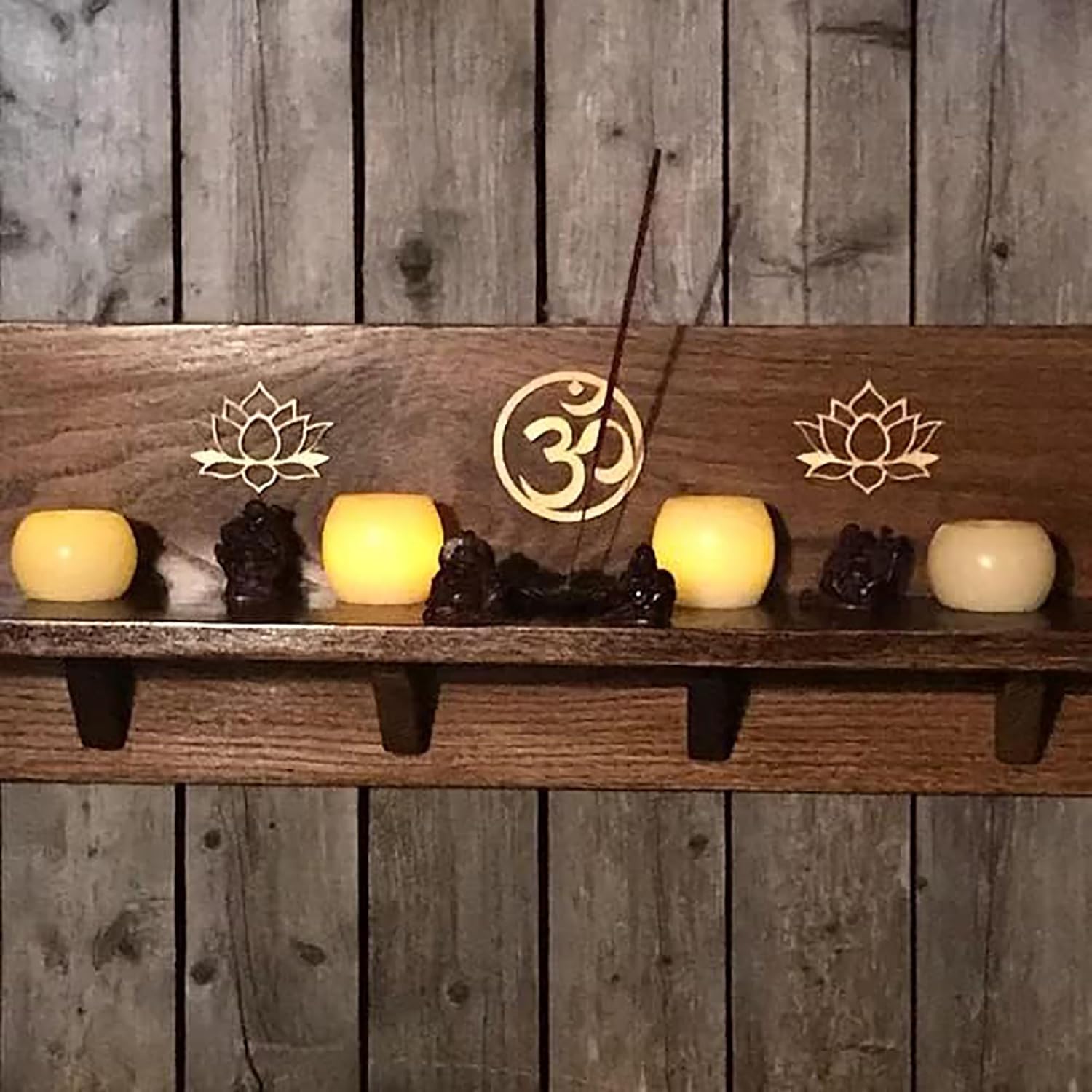 Wooden shelf with candles, incense, and decorative symbols against a wooden wall.