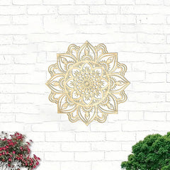Decorative metal wall art with a mandala design on a white brick wall.
