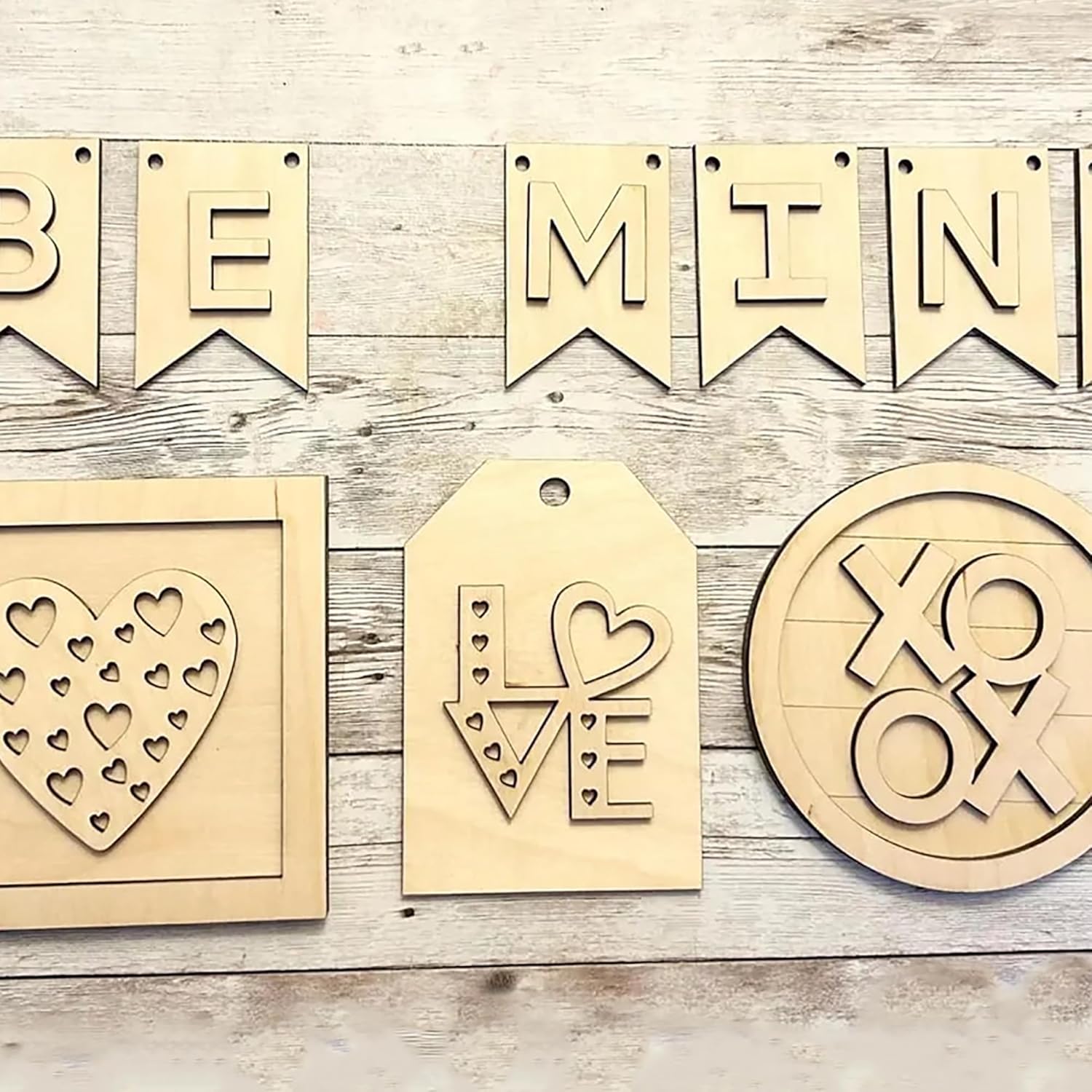 Wooden decorative items including a 'Be Mine' banner, heart-shaped tags, and a 'XO OX' design on a wooden surface.