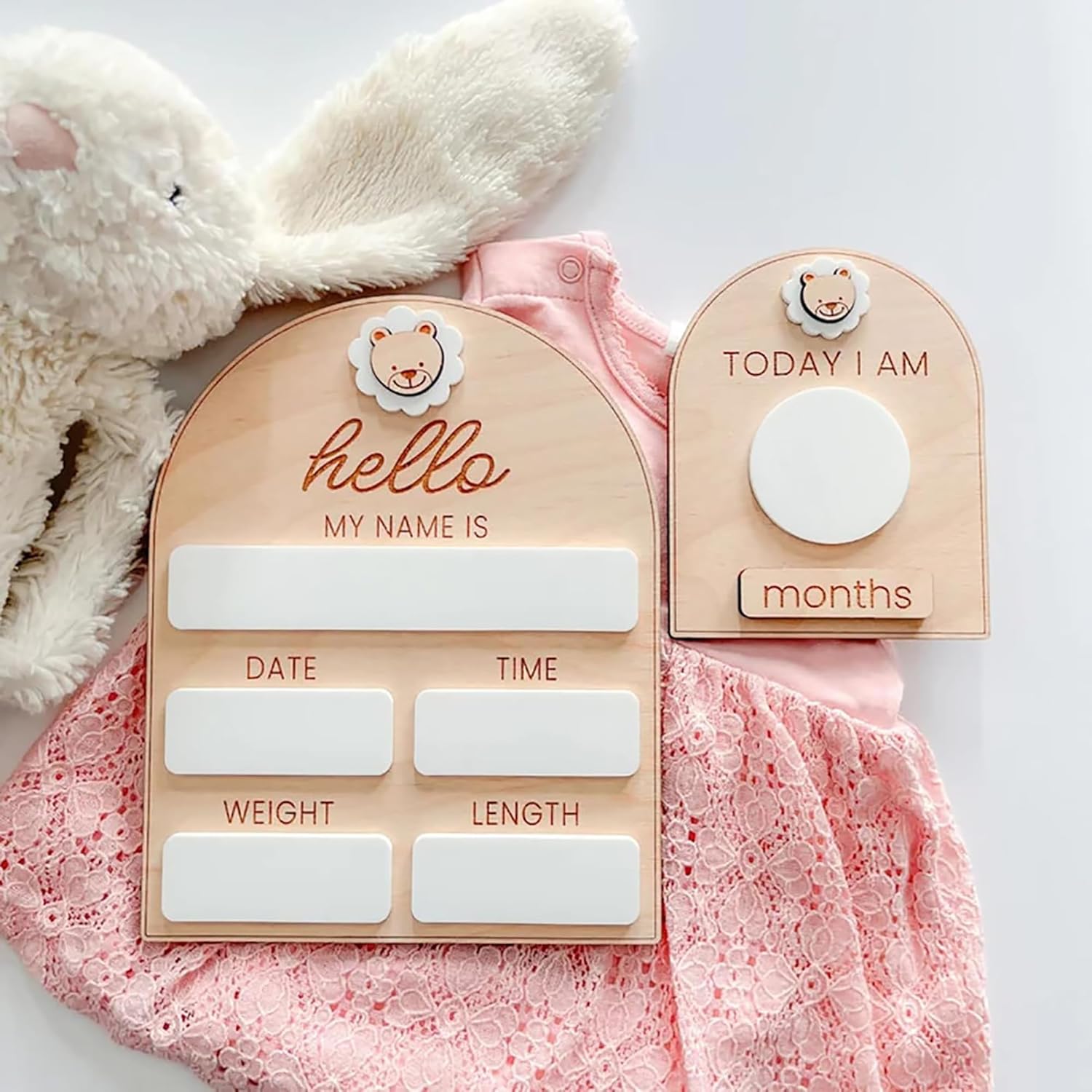 Wooden baby milestone cards with pink baby outfit and plush toy on a white background