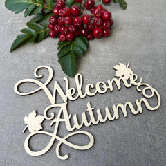 Decorative sign with 'Welcome Autumn' text on a gray background with red berries and green leaves.
