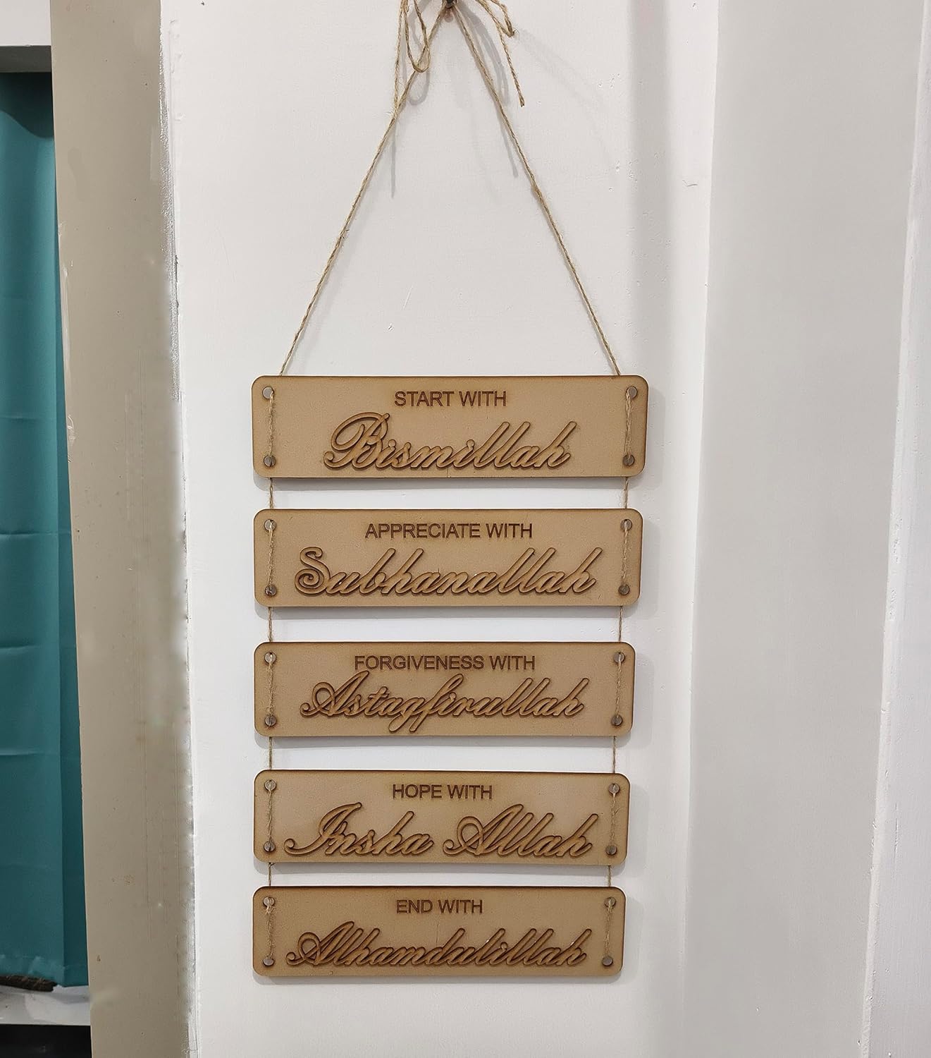 Wooden plaque with engraved phrases on a white wall.