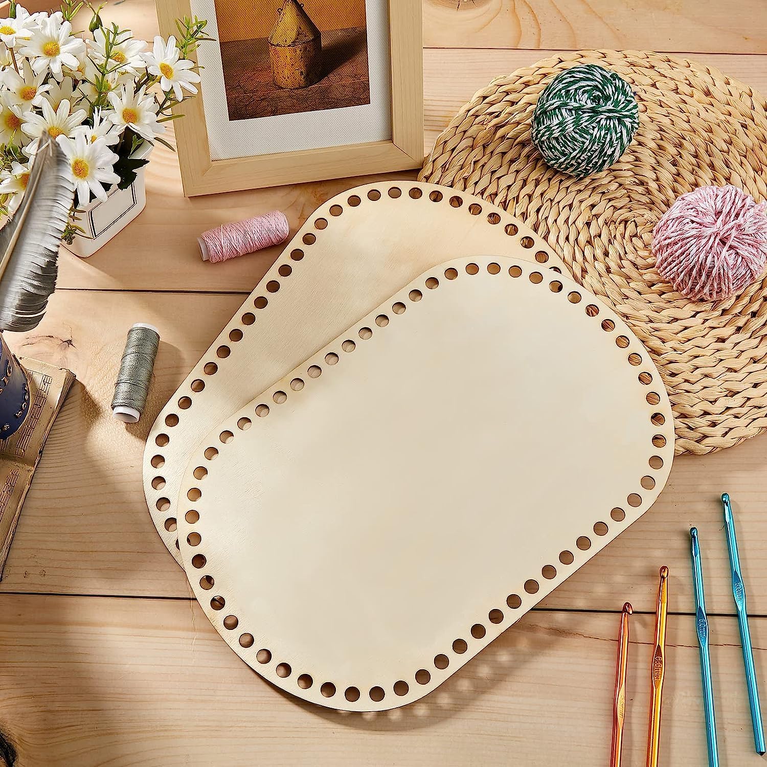 Wooden lace board with holes on a wooden surface with yarn and crochet hooks.
