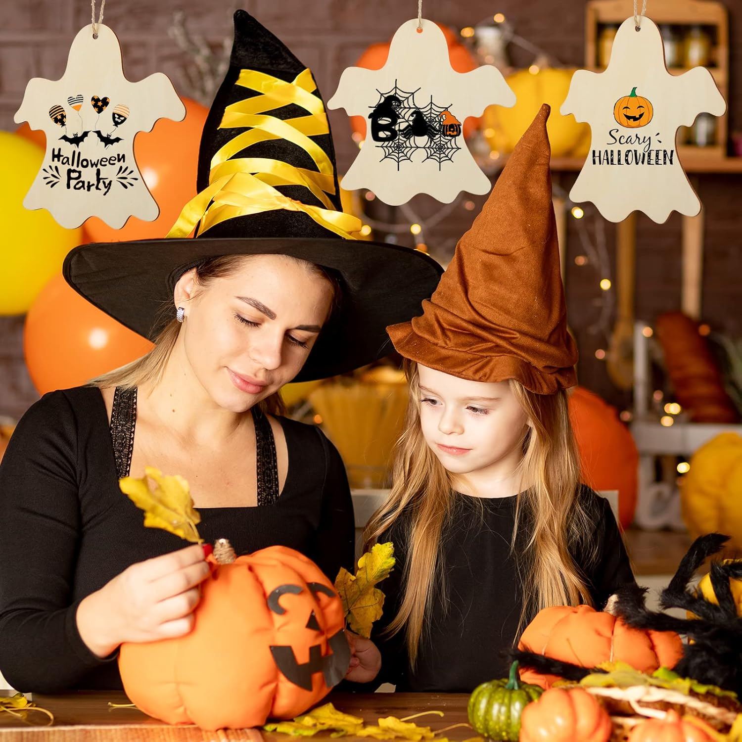Woman and child in Halloween costumes carving pumpkins with decorations around them.